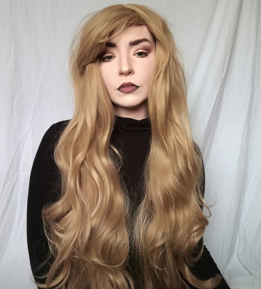 Blonde long wavy wig with bangs. Want a natural look with the wow factor?. Fawn is a light golden blonde colour. A loose wave runs through the style, with a long fringe.