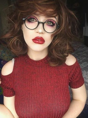 A warm brown wig with golden blonde highlights throughout. Styled into a bob thats sleek from the roots, ending in large curls. The bangs are blunt and sleek.