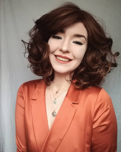 Retro vintage brown curly bob with bangs. Reminiscent of the hairstyles of the 1930s and 1940s. Film Star is a deep mahogany brown with golden highlights. Styled with big barrel curls.