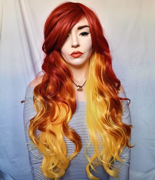 Flame - Lush Wigs UK Thick and bouncy, Flame has a deep red outer colour, and layers of yellow and orange hair underneath which peep through the lengths. It is styled in loose curls and has a heavy, side-swept fringe.