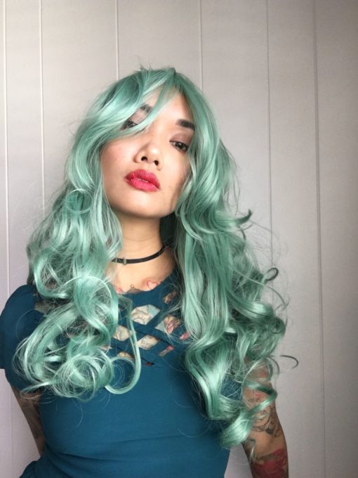 Cascading, dark mint green curls that fall past the bust. Green Revolution has a long, thick fringe that falls to one side but can be styled by the wearer.