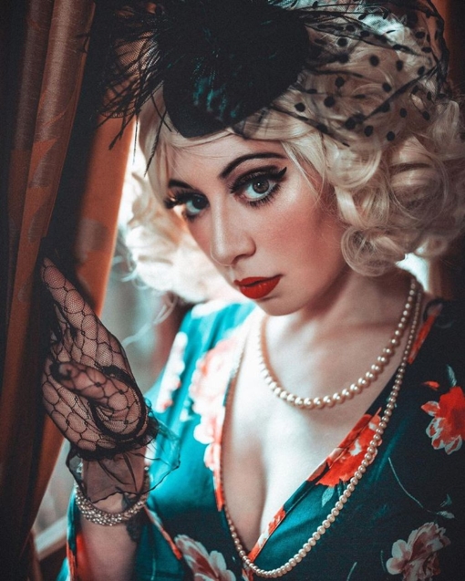 Blonde short bob wig with bangs. Moll is perfect for recreating hairstyles of the 1920s and 1930s retro era. A pale blonde colour in tight ringlet curls for glamour or loosened for a soft romantic style.