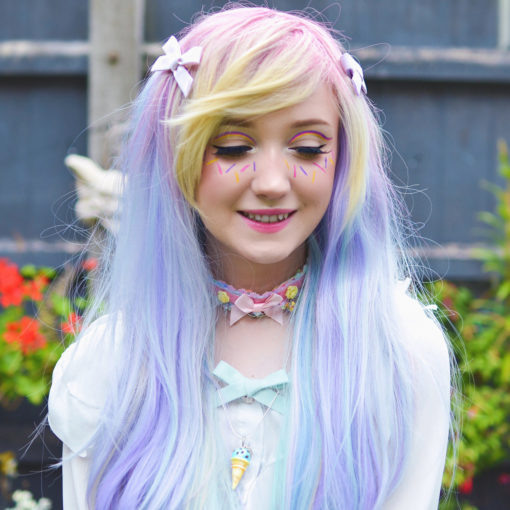 Multicolour pastel long straight wig with bangs. Candy sprinkles of pastel hues. Pink roots fade into a mix of yellow, blue, purple.