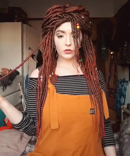 Our first dreadlock wig! Warrior Princess is a mixture of brown and bright red hair, styled into thin dreadlocks that fall in layers around the face, shoulders and chest. The wig has more volume of hair on the top, and works great styled in a half up/half down look.