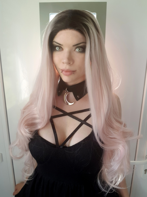 Powder pink long lace front wig with curls. Empress combines glamour with cute. A natural twist of black roots that fade into a pastel pink hue. Full of volume from the roots, styled in big bouncy curls.