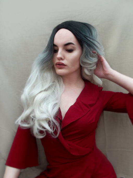 Dark roots fade from black/dark grey, into lighter grey and then bright white blonde. A beautiful long, middle parted wig, styled in curls through the ends.