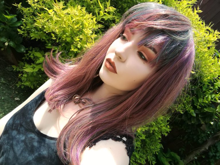 This Vivid wig is a mixture of purples, blues and muted lemon and green tones, from roots to tips. Styled sleek with long layers falling to the waist. The fringe is long and sleek, wear it to the side or parted for curtain bangs.