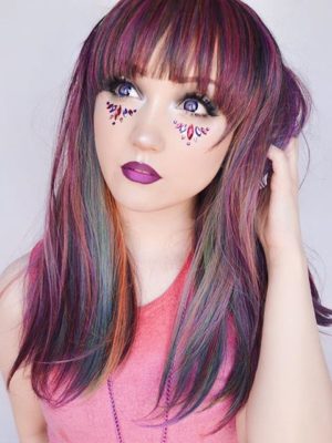 This Vivid wig is a mixture of purples, blues and muted lemon and green tones, from roots to tips. Styled sleek with long layers falling to the waist. The fringe is long and sleek, wear it to the side or parted for curtain bangs.