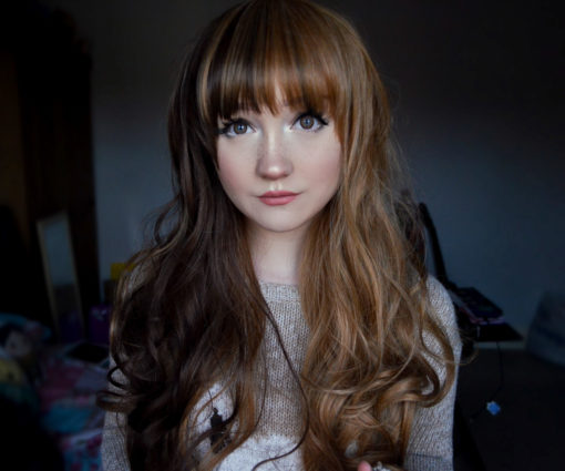 Brown long curly wig with bangs. Brownie is a natural style with a colour block of chocolate brown colour at the front. That runs through the fringe and the length of blonde hair for a playful accent. The fringe is straight and blunt or long for extra layers around the face. Long layers end in curls that fall to the waist, allows you to play with different styles.