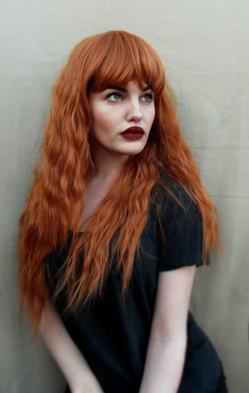 This natural ginger colour from roots to tips. Made up of copper and amber tones. Styled in crimped waves in layers that fall to the waist. With a sleek thick fringe.