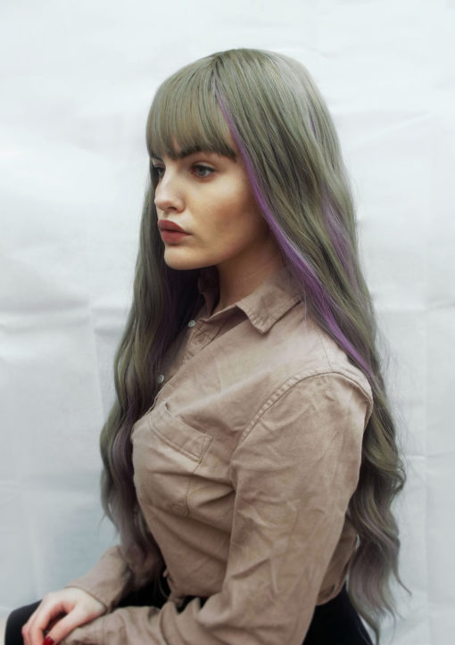 Soft and wavy, Rosa is such a pretty style. A soft grey with lilac streaks running through it, set in long, loose waves. This wig falls around bust length and has a blunt wispy fringe. This wig has a realistic skin top parting.