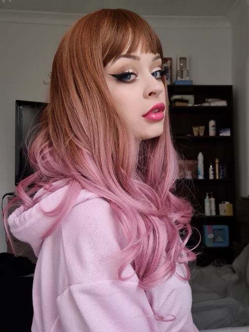Brown and pink straight wig with curls. Want a little rose-gold with a pop of pink? Rosebud has Light brown roots that lead into a curly soft rose ombre.