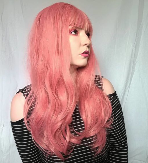 Long and lovely, this pink wig has an unusual subtle tone to it, giving it a rosy pink glow. Love the unusual colour mix set in long waves with a full fringe. Bound to get you noticed!