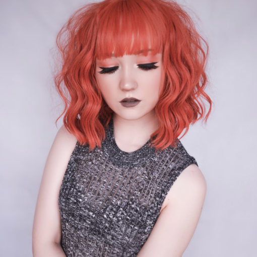 Red orange wavy bob wig with bangs. Tiger is one of our vibrant and rich styles that comes in a deep burnt red shade, in loose beachy waves.