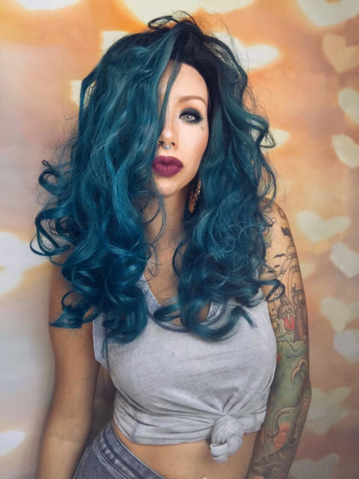 Gorgeous, tumbling curls in a deep, jewel blue. We are in love! This wig has a contrasting black root to give it a bit of an edge. The loose curls give it plenty of glamour, and the length falls around the bust.