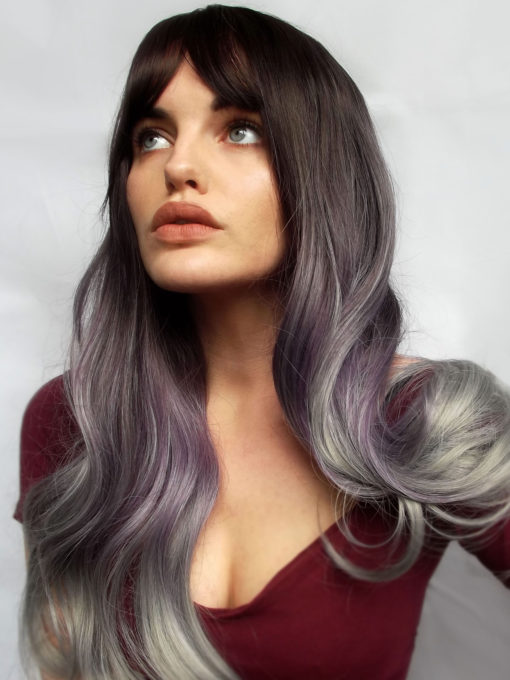 Black and purple long wig with bangs. The epitome of gothic glamour. Sabbath has dark brown roots with a mix of purple and grey tones creating this ombre with grey dip dye ends that brings this style into its own. This long layered cut has plenty of movement, with large barrel curls at the ends.