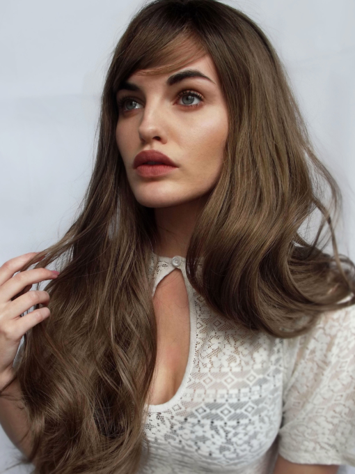 Dark blonde long curly wig with bangs. Willow doesn't fail when it comes to 70s hair. Soft and natural with a combination of dark blonde and light brown shades with dark brown shadowed roots. 