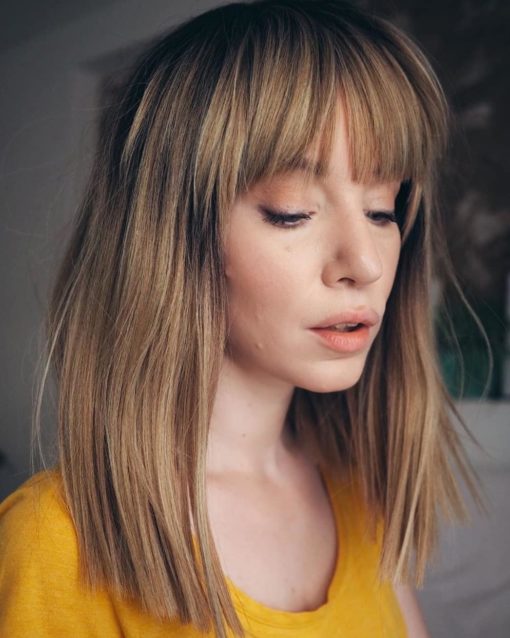 Mono has black shadowed roots for a natural vibe, that melts into this honey blonde colour. Poker straight with a sleek fringe.