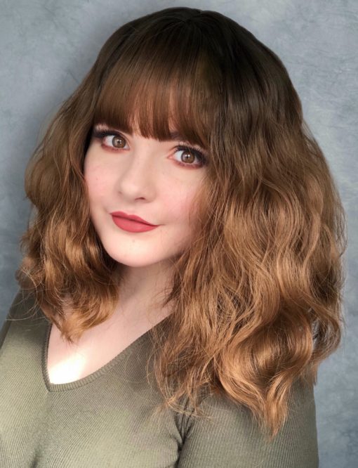 Brown wavy long wig with bangs. Simple and natural is Catrin. Brown shadow roots blend into a light brunette colour with golden highlights. We love this wavy style.