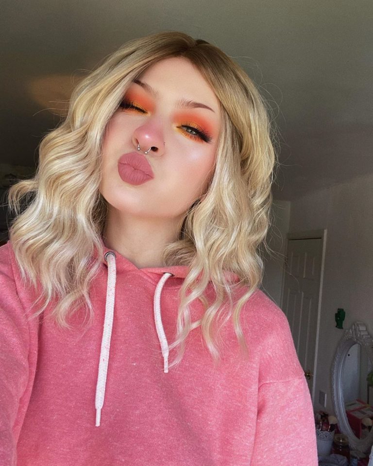 Eleri - Lush Wigs UK This long bob with dark brown shadow roots blend into a warm blonde hue. Styled in a loose wave with a sleek blunt fringe.