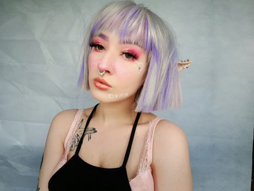 Hina - Lush Wigs UK Silver grey bob wig with bangs. Hina is a striking colour block A-line bob, with matching choppy blunt fringe. A silvery grey shade dominates, but brought to life with baby pink and purple pastel highlights running through it. A sleek and blunt style carries this distinctive look.