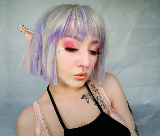 Hina - Lush Wigs UK Silver grey bob wig with bangs. Hina is a striking colour block A-line bob, with matching choppy blunt fringe. A silvery grey shade dominates, but brought to life with baby pink and purple pastel highlights running through it. A sleek and blunt style carries this distinctive look.
