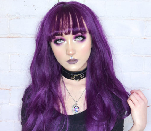 Purple long curly lace front wig with bangs. A rich, jewel toned purple hue. The cut is long and finished with loose curls. This is our only lace front with a full fringe. Deep Purple looks vibrant paired with bright looks or striking with dark monochrome outfits.