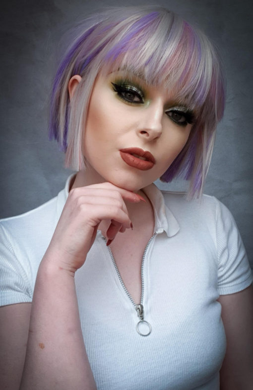Hina - Lush Wigs UK Silver grey bob wig with bangs. Hina is a striking colour block A-line bob, with matching choppy blunt fringe. A silvery grey shade dominates, but brought to life with baby pink and purple pastel highlights running through it. A sleek and blunt style carries this distinctive look.