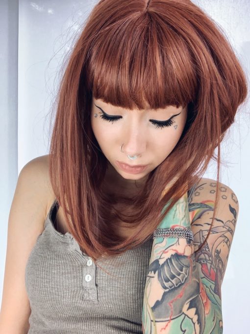 Brown straight long bob wig with bangs. Saffron is a natural granulated cut. A mixture of brunette and cinnamon undertones. A sleek long bob with a blunt fringe. A combination of stylish and sassy.