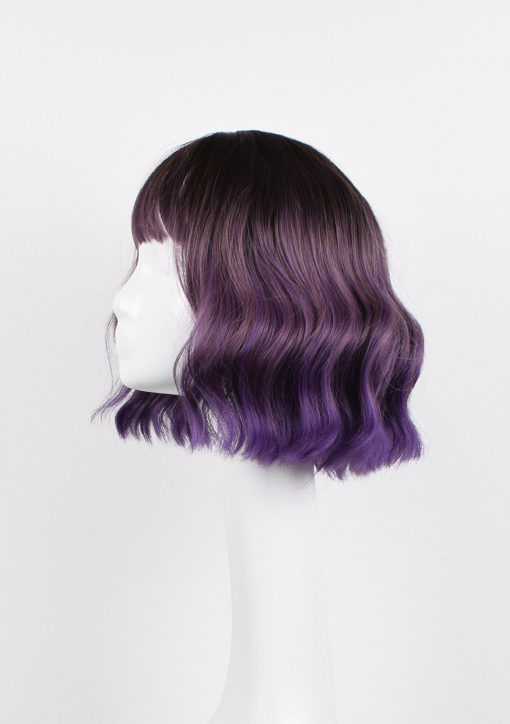 Purple wavy bob wig with bangs. Bruised violet is a light choppy bob. Warm brown shadowed roots give a natural feel to the look. A mix of purples and lilacs through the lengths.