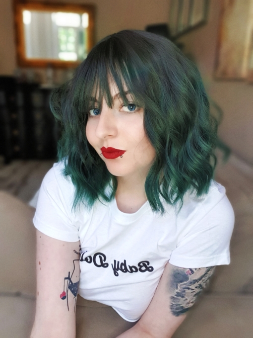 Emerald falls is a bob that falls just to the shoulders. Black coal shadowed roots give a natural feel to the wavy style that has a forest green ombre. A light fringe frames the face.