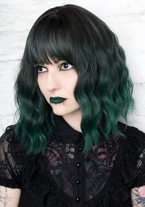 Emerald falls is a bob that falls just to the shoulders. Black coal shadowed roots give a natural feel to the wavy style that has a forest green ombre. A light fringe frames the face.