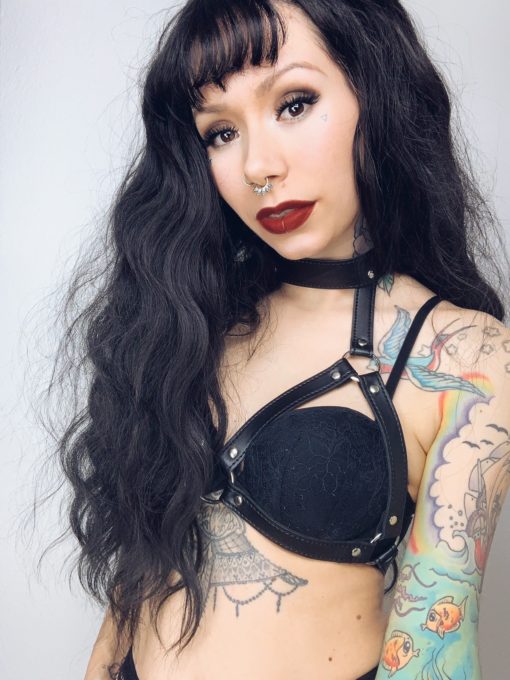 Black long wavy wig with bangs. Conjure some gothic glamour with Apparition. Warm black tone with long loose curls with invisible layers to add body and movement to the look.