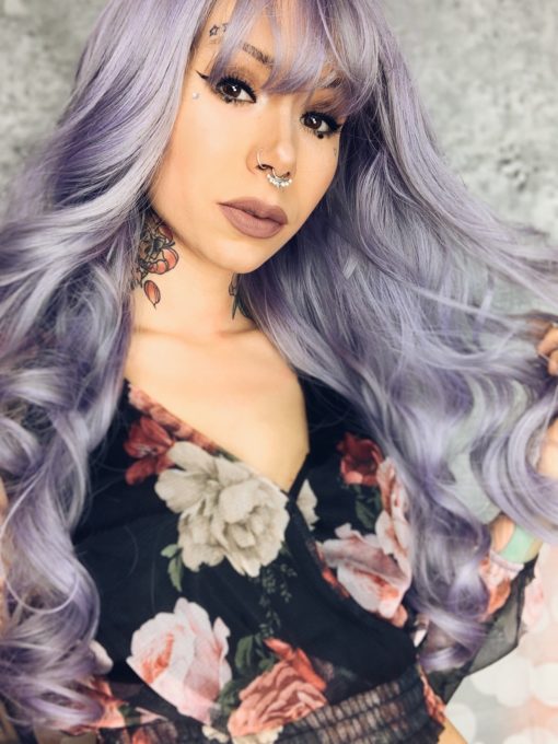 Lilac and grey curly wig with bangs. Harmony is a concoction of deep pastel lilacs with muted silver highlights. Styled in barrel curls. 