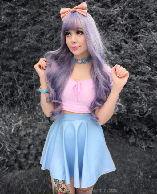 Lilac and grey curly wig with bangs. Harmony is a concoction of deep pastel lilacs with muted silver highlights. Styled in barrel curls. 