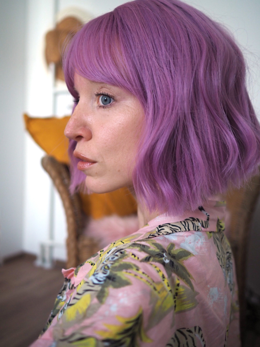 A jaw skimming deep lilac bob from roots to tips. Sleek from the centre parting with a light fringe. Its blunt cut is thick and full with a slight wave for texture. Lightweight and easy to maintain.