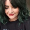 Green ombre wavy bob wig with bangs. Emerald falls is a light graduated choppy bob. Black shadowed roots give a natural feel to the look. A dark forest green colour through the lengths.