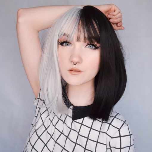 Black and white split bob wig. Domino takes on the dramatic colour divide. This bold statement of black and platinum hues. Split down the centre parting and carrying the colour through the fringe.