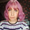 Purple wavy bob wig with bangs. Bruised violet is a light choppy bob. Warm brown shadowed roots give a natural feel to the look. A mix of purples and lilacs through the lengths.