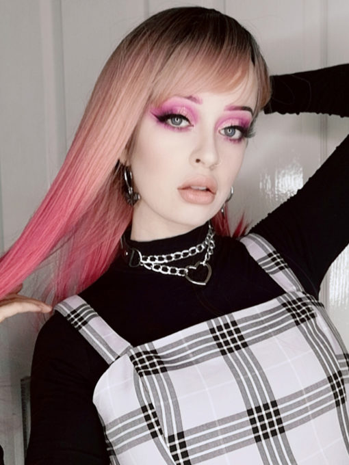Pink ombre long straight wig with dark roots. Kyandi creates an unusual mixture of dark grey roots that melt into a dusky pink, blends to a magenta pink that dominates the sleek length of this style.