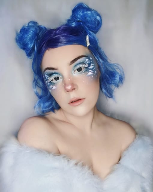 Blue wavy bob wig with bangs. Blueberry takes a mixture of pastel tones. A light pinky-purple dyes the roots and wispy fringe, that melt into a sky blue colour. Beachy waves give texture and body, falling just above the shoulders.