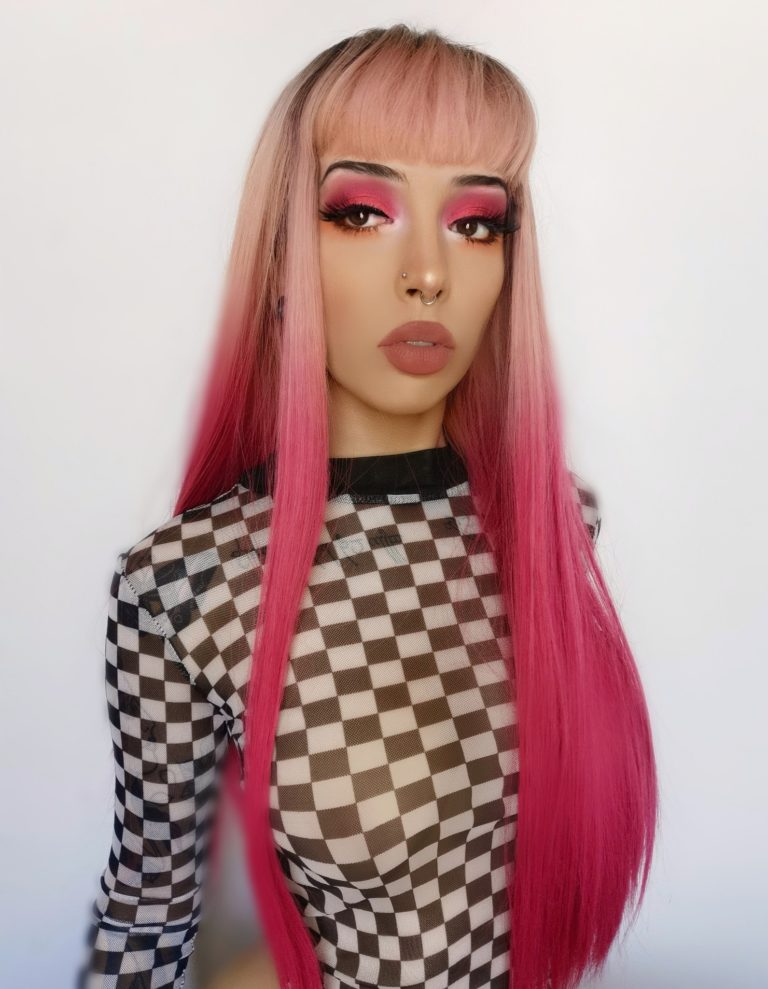 Kyandi - Lush Wigs UK Pink ombre long straight wig with dark roots. Kyandi creates an unusual mixture of dark grey roots that melt into a dusky pink, blends to a magenta pink that dominates the sleek length of this style.