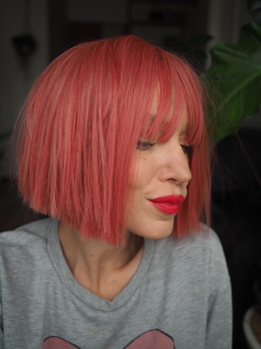 Make a statement in this striking style. Fresh rose hues from roots to tips set this poker straight blunt cut.