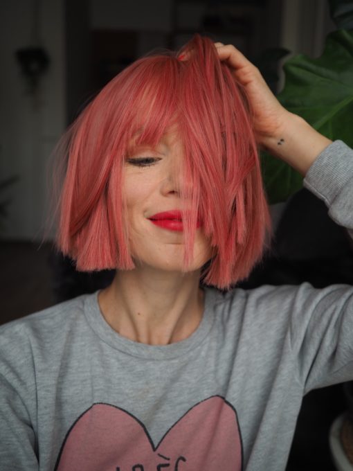 Make a statement in this striking style. Fresh rose hues from roots to tips set this poker straight blunt cut.