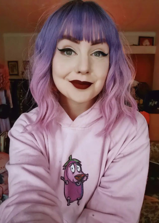 Purple and pink, long wavy bob wig with bangs. Sugarpop takes on colour dimensions, this pretty colour mix of cool brown shadowed roots, that become a soft purple ombre colour around the crown of the head and in the fringe. Melting into a light pink dip dye ends.