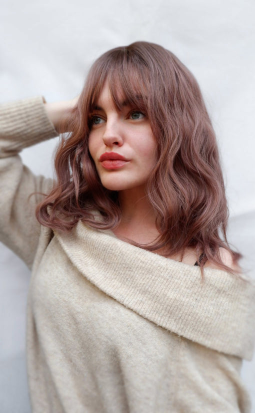 Yoake is a long bob (lob) with brown shadow roots that run into the fringe to frame the face. We love the mix of warm chocolate browns and dark pinks to create this beautiful rosewood colour. Dishevelled waves fall just to the collarbones.