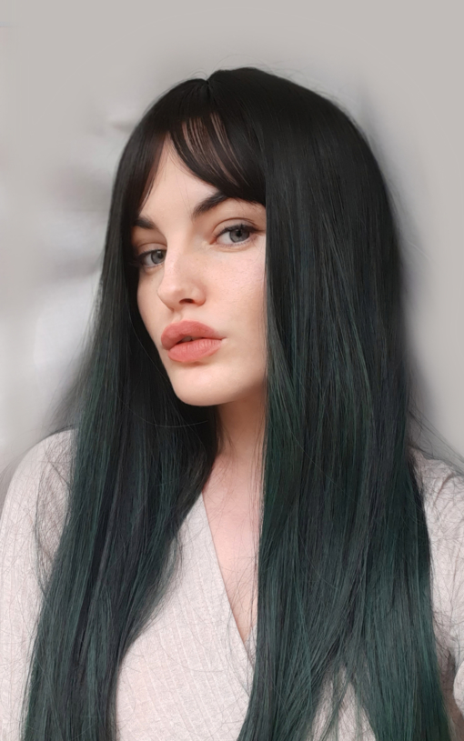 Dark green straight wig with bangs. We have iconic gothic vibes with Midori, a barely there twist on colour. Black roots blend into sleek sage ombre. 