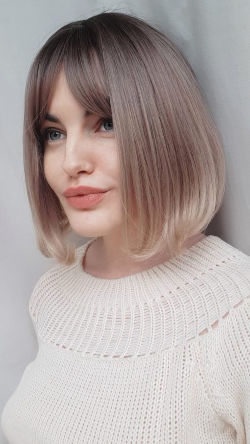 Blonde straight wig with bangs. A vintage style updated with colour. Amai is a natural twist of brown roots that blend into a dusky pink and lilac ombre, with a sandy blonde dip dye.