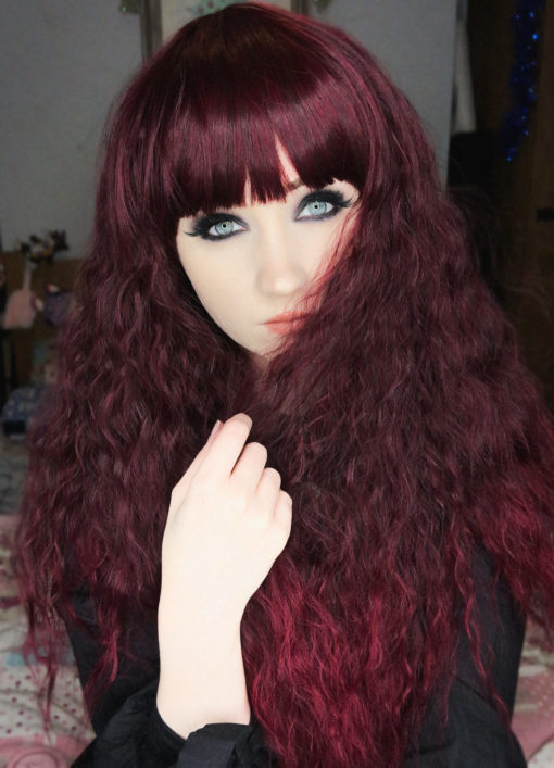 Purple long wavy wig with bangs. Ruby has amplified waves that produce this big, voluminous style. A concoction of purple tones with deep ruby hues.