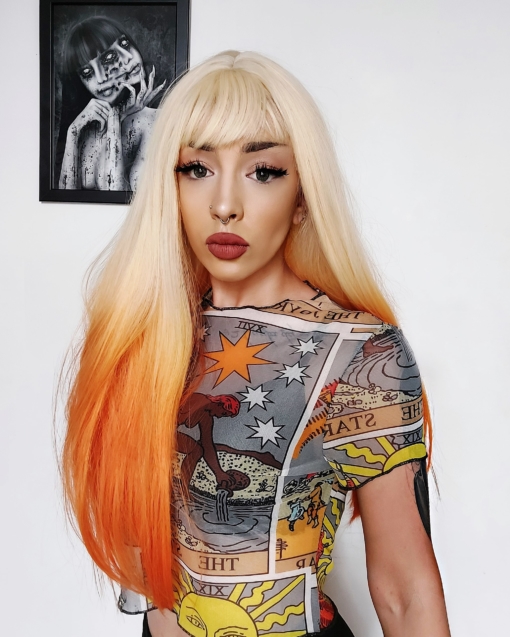 Orange and blonde long straight wig with bangs. Citrus reminds us of sunsets with its fresh and fun take on blonde, that blends into bright orange ombre.